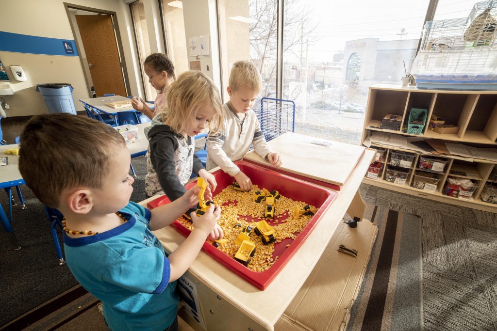 kids at daycare playing with trucks in a bin