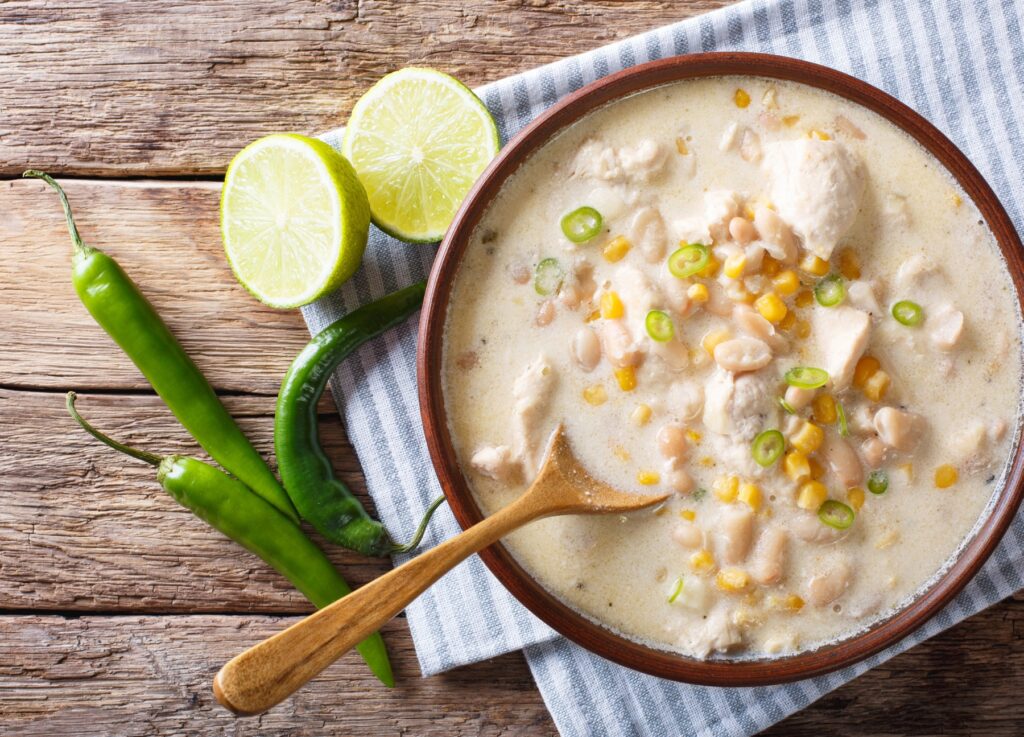 A bowl of creamy white chicken chili with lime and fresh herbs.