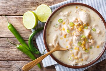 A bowl of creamy white chicken chili with lime and fresh herbs.
