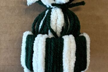 A handmade green and white yarn hat ornament.