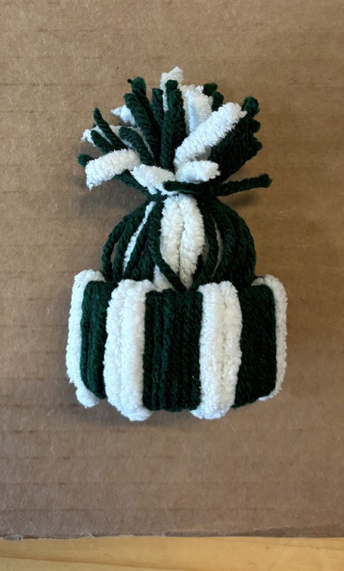 A handmade green and white yarn hat ornament.